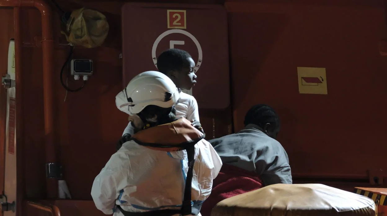 Un miembro de Salvamento Marítimo asiste a uno de los seis niños que viajaban en una patera rescatada a 150 kilómetros de Canarias