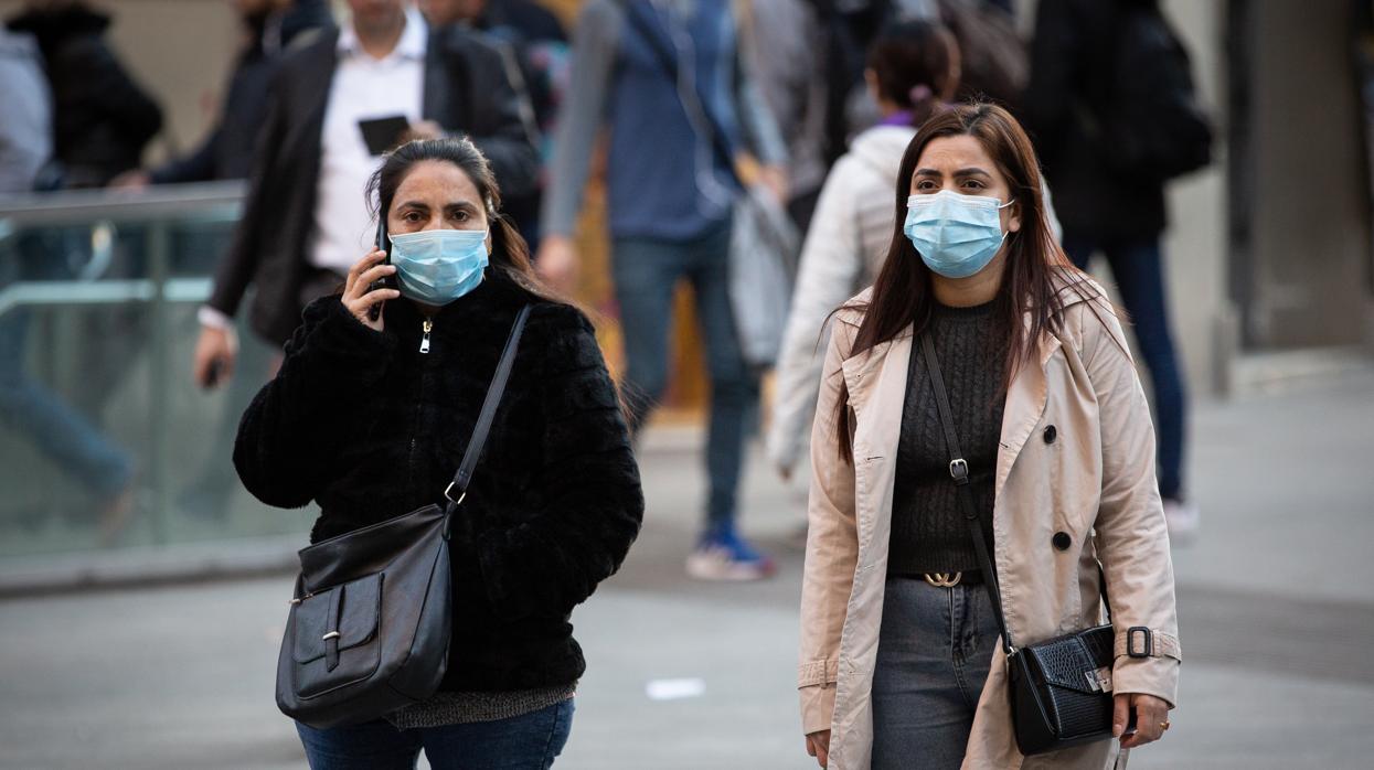 Dos mujeres con mascarillas por la calle