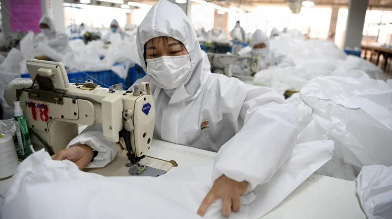 Trabajadores chinos en una fábrica textil de Whenzou usando mascarilla