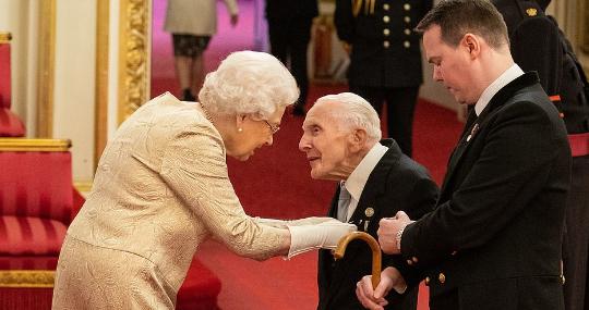 La Reina de Inglaterra coloca las condecoraciones con guantes