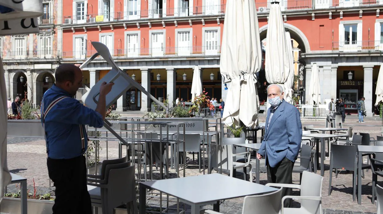 Un camarero recoge esta mañana la terraza de un establecimiento de la Plaza Mayor