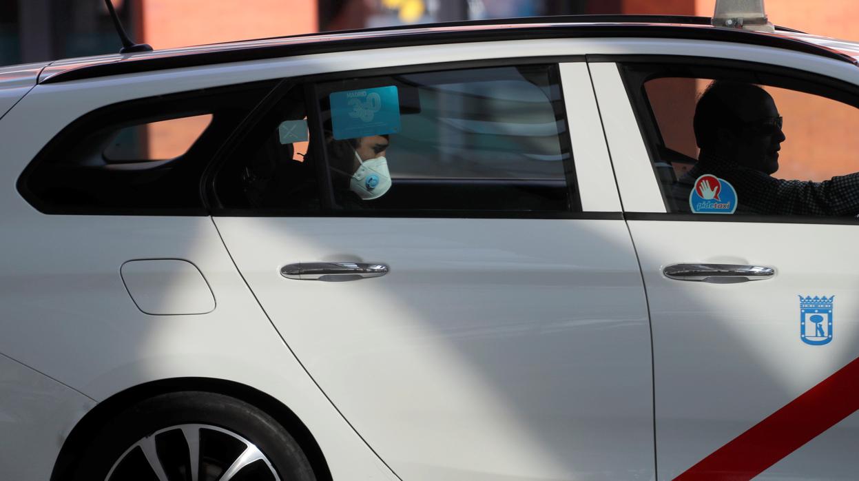 Un viajero con mascarilla en un taxi de la capital