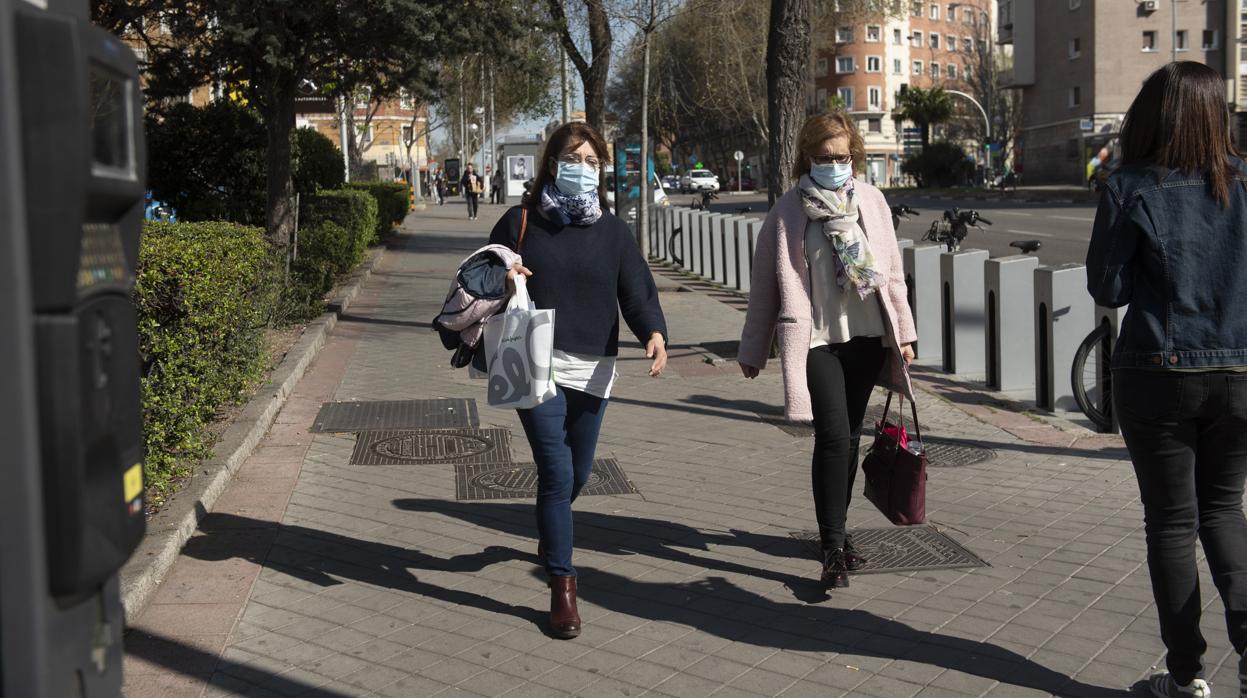 Dos mujeres con mascarillas caminan por una calle de Madrid