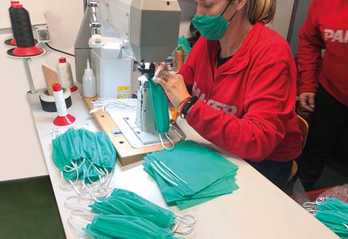 Una de las trabajadores de la empresa en la máquina de aparado cosiendo mascarillas