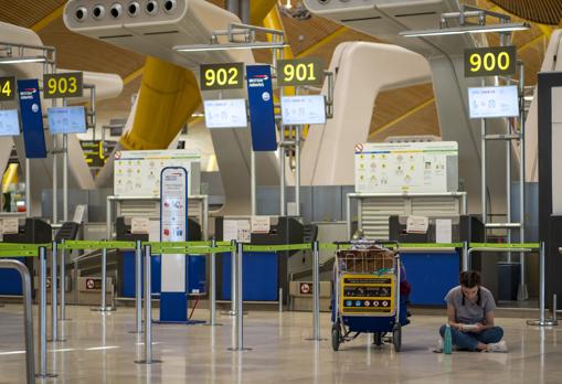 Una pasajera espera la salida de su vuelo, delante de varios mostradores cerrados