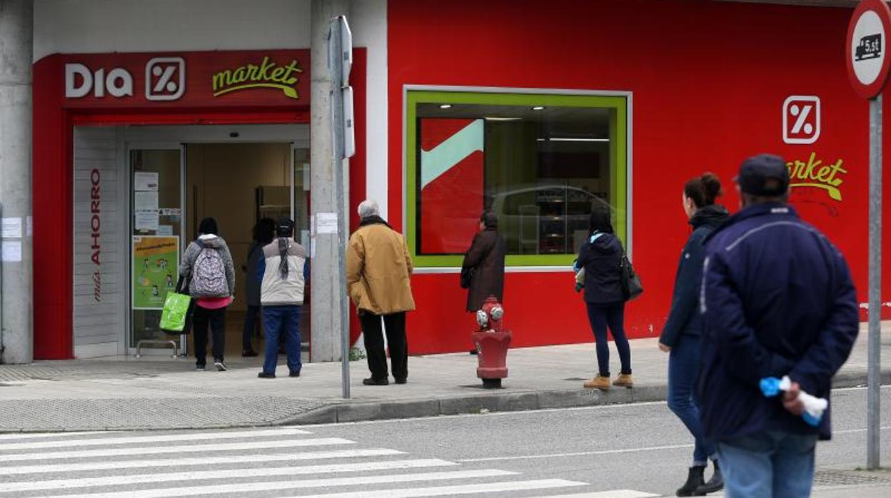 Cola de usuarios a la puerta de un supermercado guardando el control de acceso