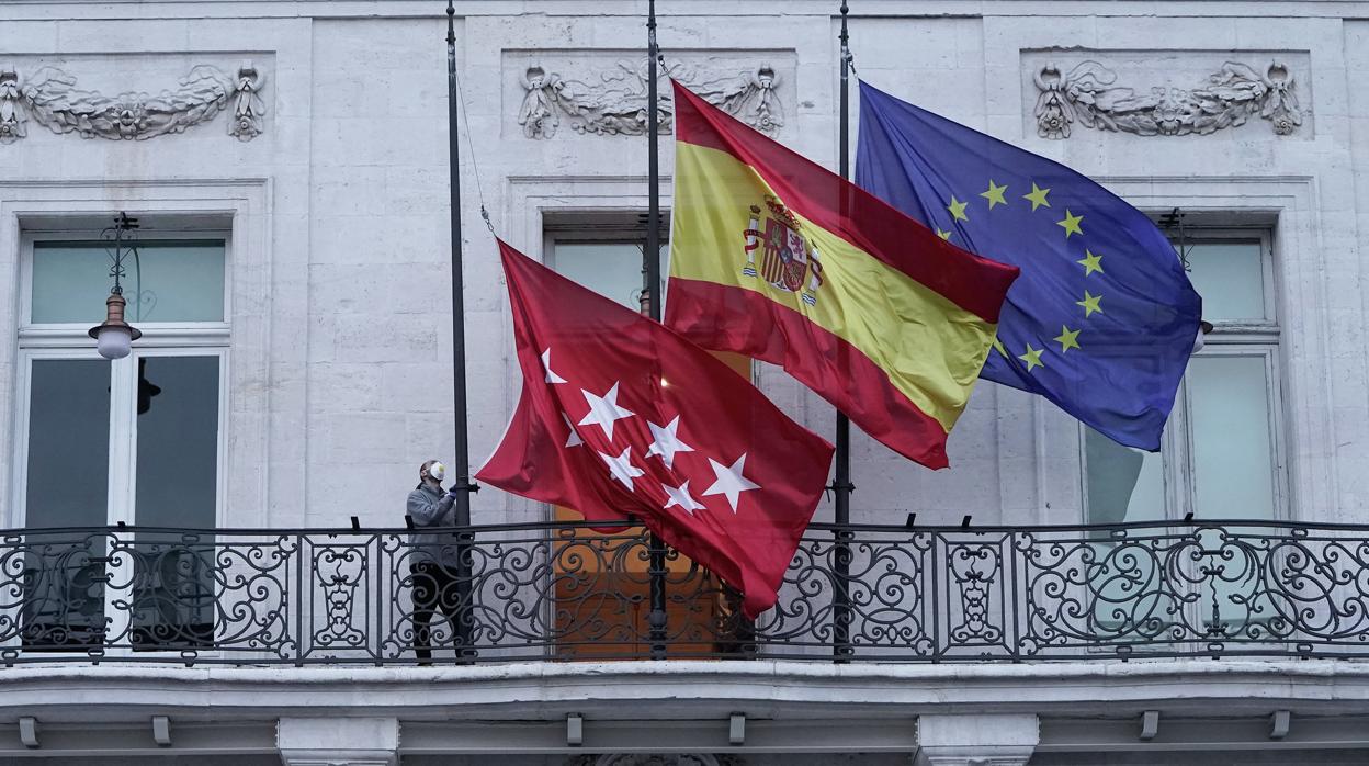 Las banderas del balcón principal de la Real Casa de Correos, en la Puerta del Sol, ondean a media asta