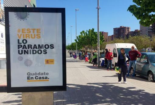 Consumidores haciendo cola a distancia prudencial para comprar en un supermercado, este viernes en Alicante