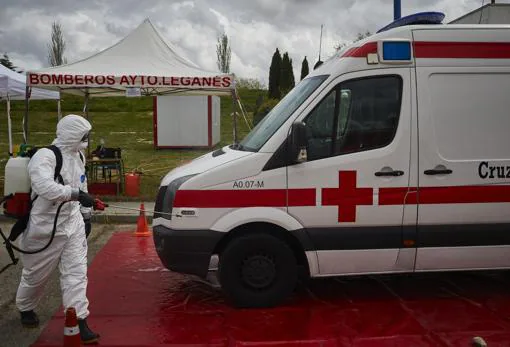 Un operario desinfecta un vehículo de Cruz Roja, en Leganés