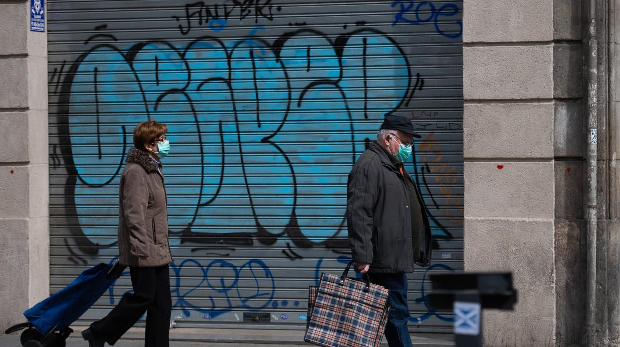 Dos personas con mascarilla, camino de la compra en Barcelona