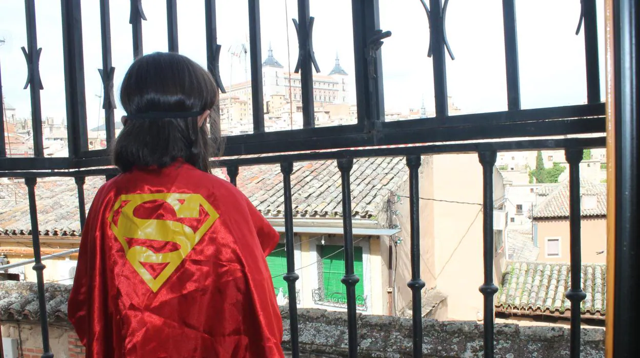 Manuela, disfrazada de superheroína, contempla la calle desde el balcón de su casa, su único desahogo