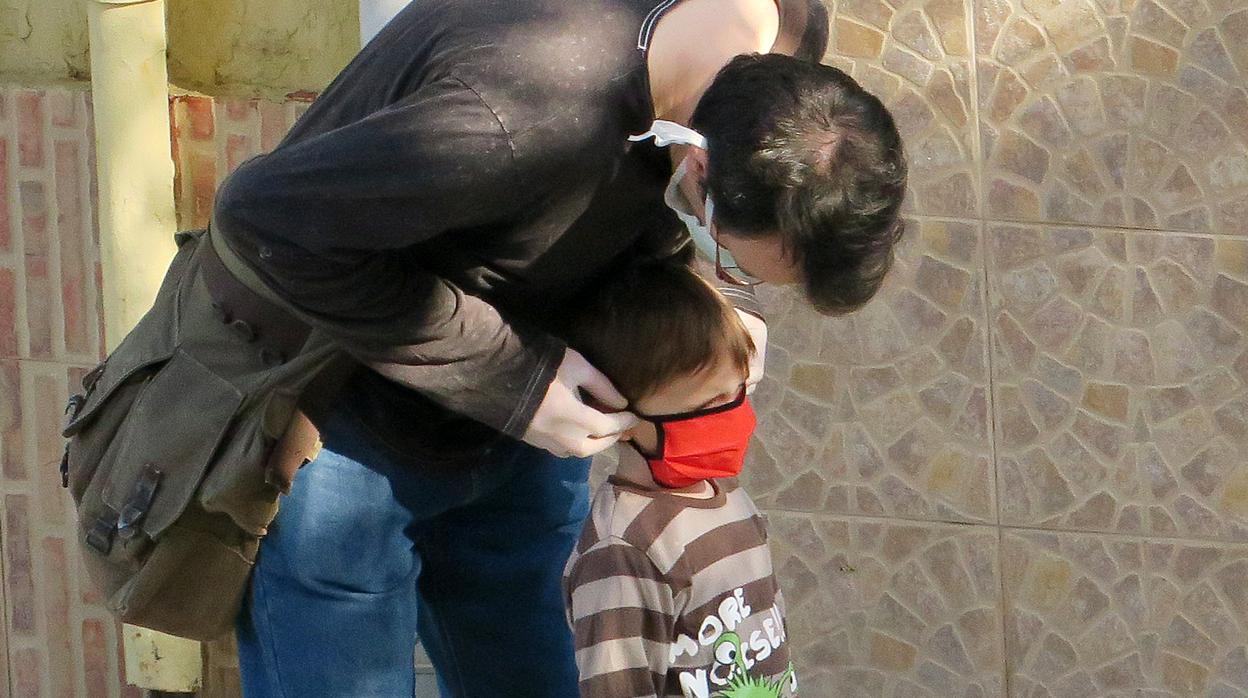 Imagen de un padre colocando la mascarilla a su hijo en la calle