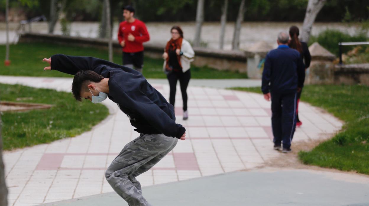 Un joven con su monopatin y adultos de paseo en este primer día en el que pueden salir