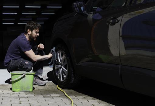 Eduardo lava las llantas de un coche, en otro taller, de chapa y pintura