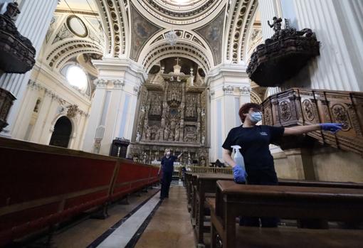 Personal de limpieza y mantenimiento en la nave central de la Basílica del Pilar, con su espectacular retablo de alabastro al fondo