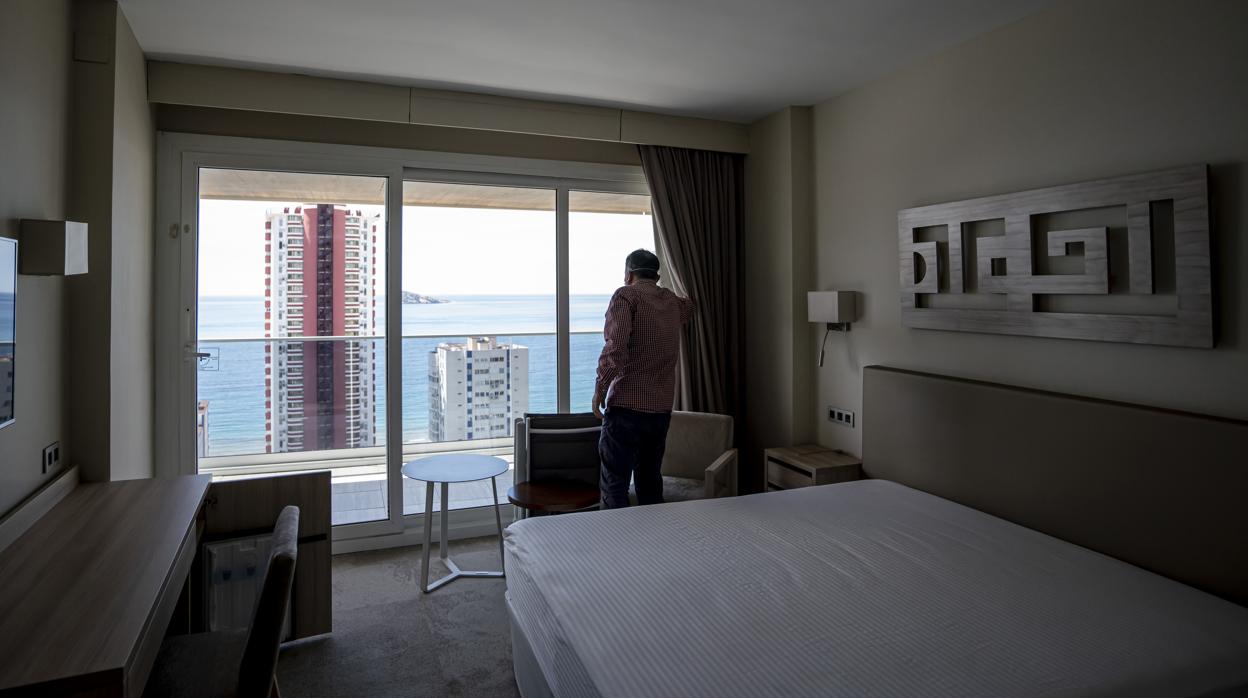 Imagen de un hombre contemplando las vistas desde la ventana de un hotel en Benidorm