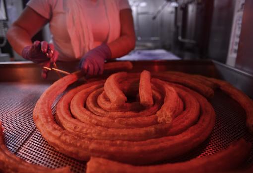 Una empleada recorta porras en la caseta de la churrería