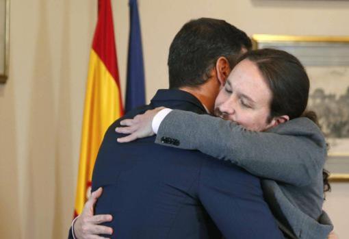 El presidente en funciones y Pablo Iglesias se abrazan en el Congreso de los Diputados tras firmar el acuerdo de Gobierno