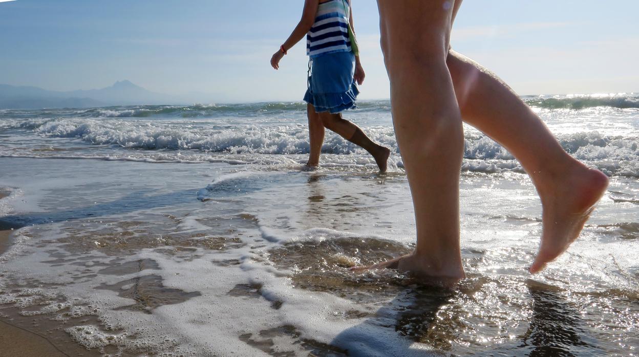 Imagen de dos mujeres paseando por una playa de Alicante