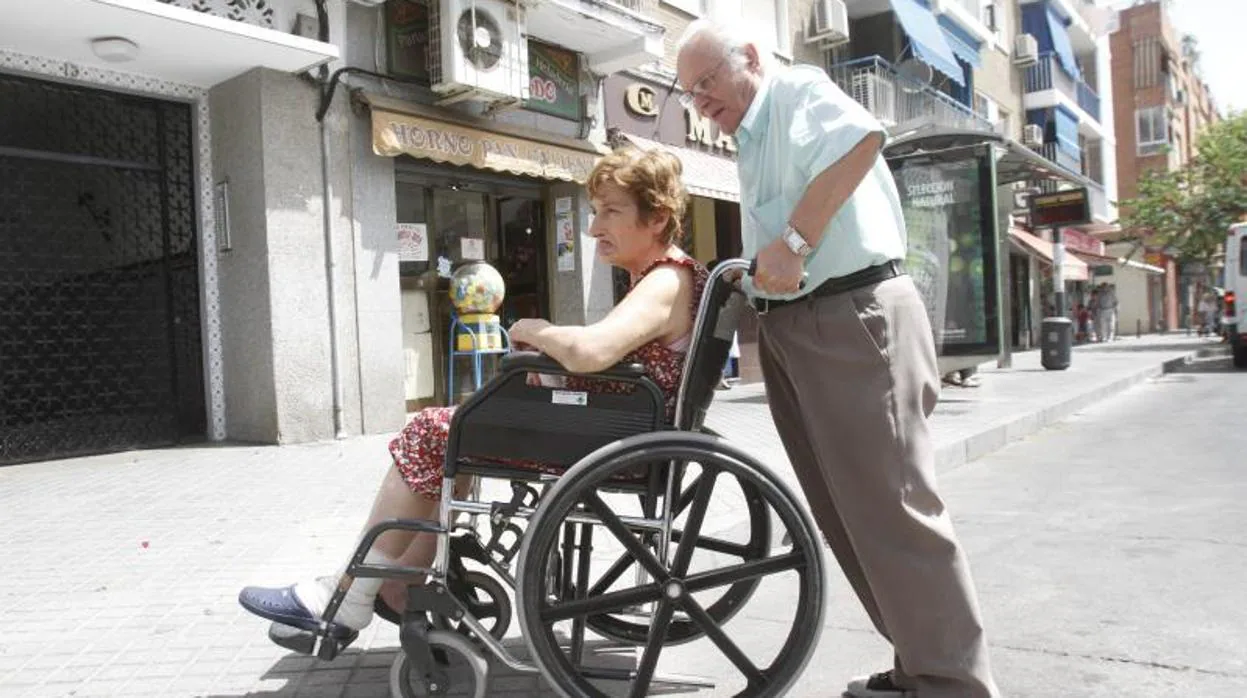 Un hombre ayuda a su mujer a desplazarse en silla de ruedas