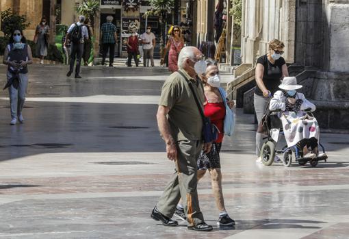 Imagen de varias personas paseando por Valencia con mascarilla