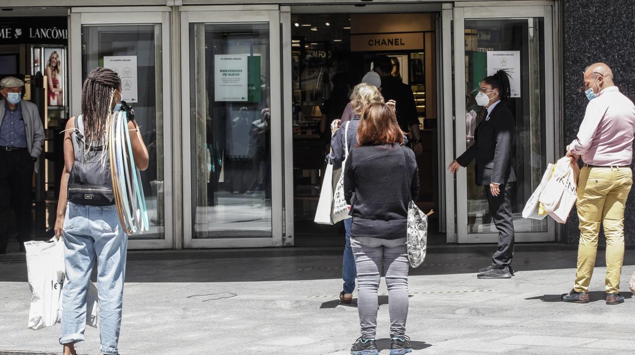 Colas con distancias de seguridad en el acceso a un centro comercial