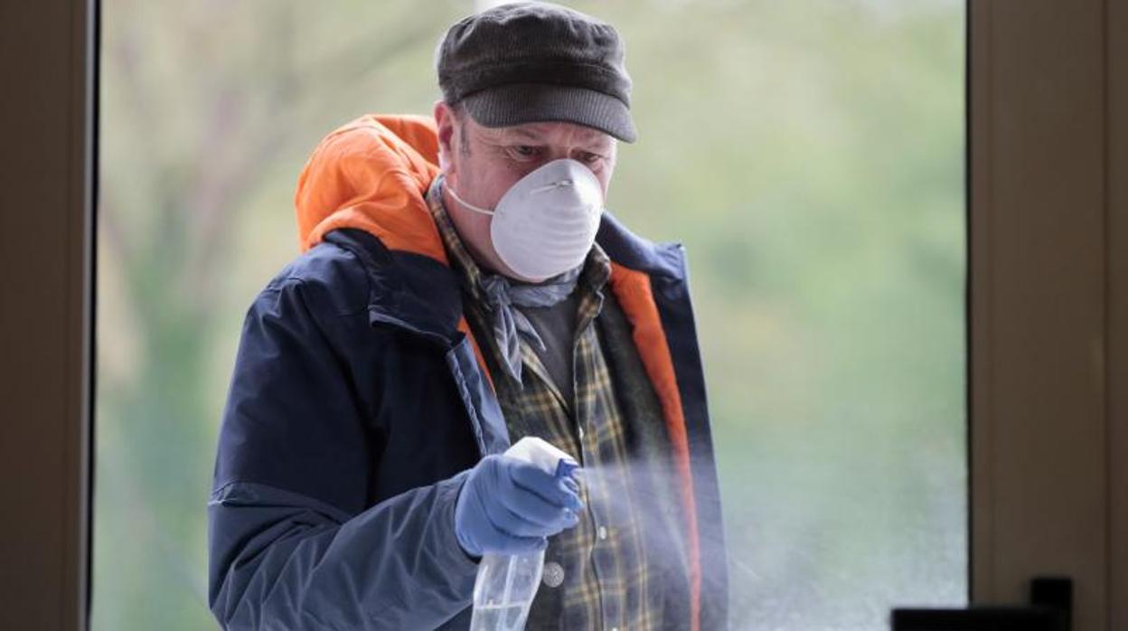 Un hombre desinfectando para acabar con el coronavirus en un edicifio de Lugo