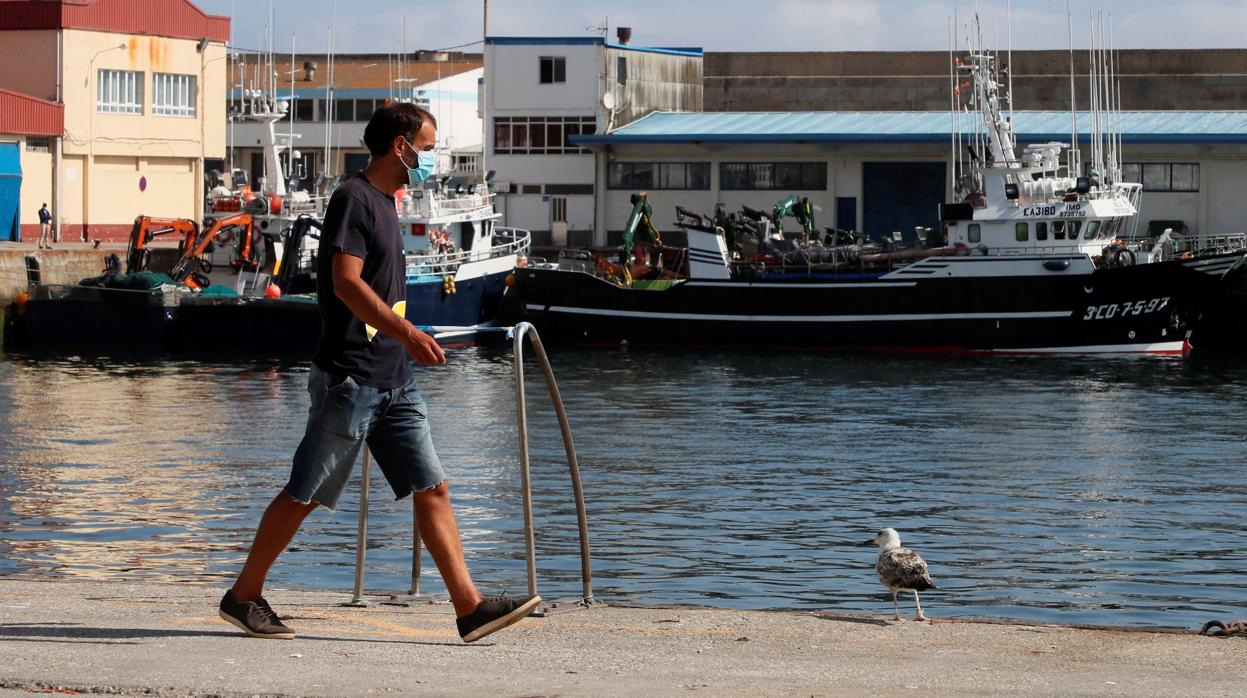 Un trabajador camina este jueves por el puerto de Burela, el municipio de A Mariña con más afectados por el brote de coronavirus