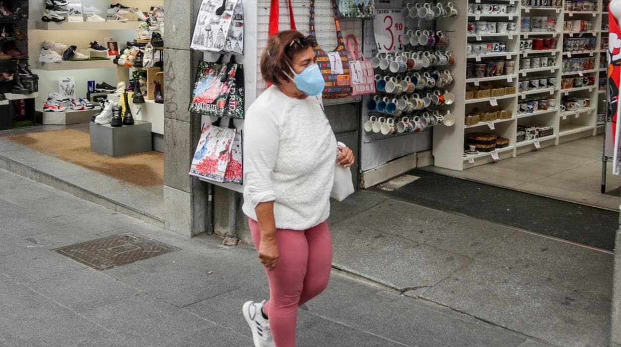 Una persona, con mascarilla, en una calle comercial de Madrid capital
