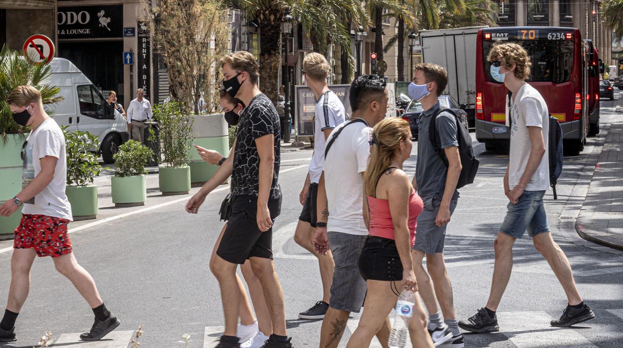 Imagen de un grupo de personas paseando por Valencia con mascarilla