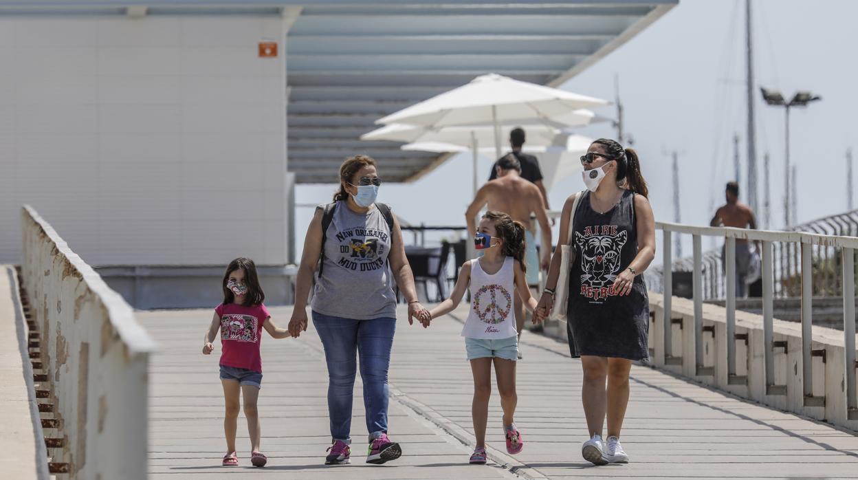 Varias personas con mascarilla pasean por la Marina de Valencia