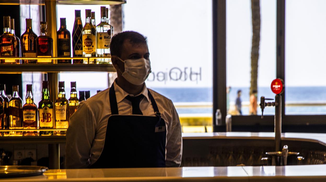 Imagen de un camarero con mascarilla en un bar