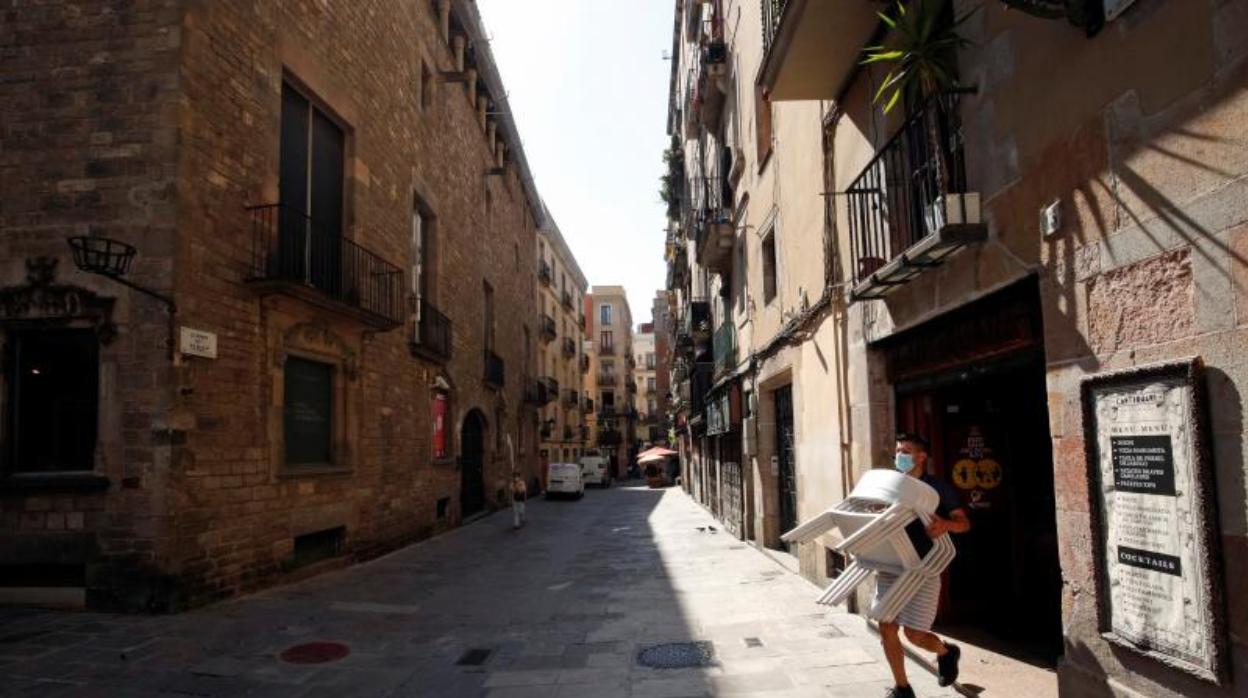 Un empleado de un bar montando la terraza en el Gótico de Barcelona