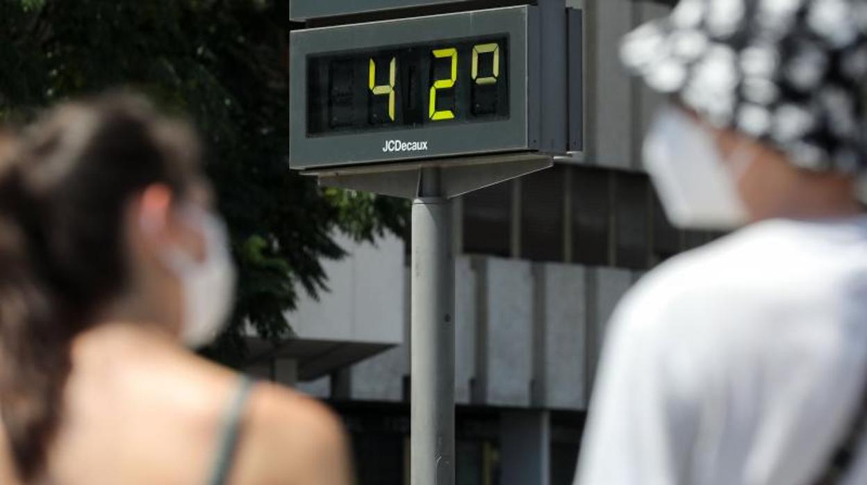 Dos traseúntes observan un termómetro en la calle este viernes en Valencia