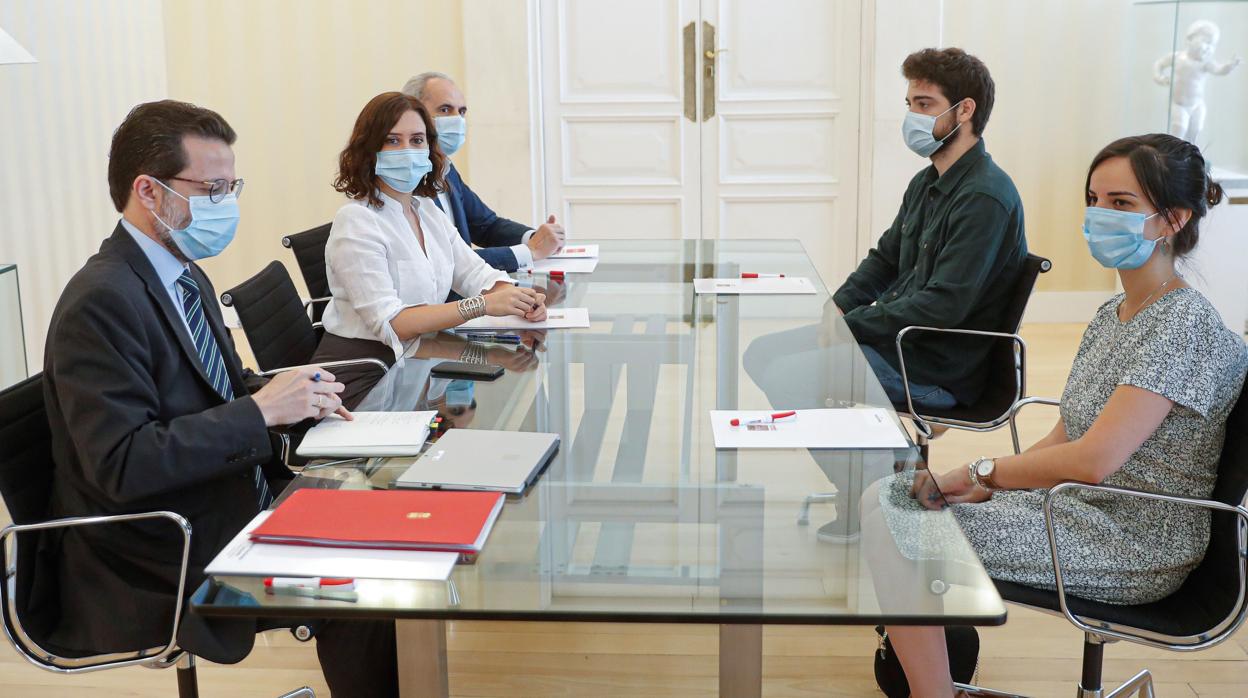 Los consejeros de Hacienda y Sanidad e Isabel Díaz Ayuso, junto a los representantes de los MIR