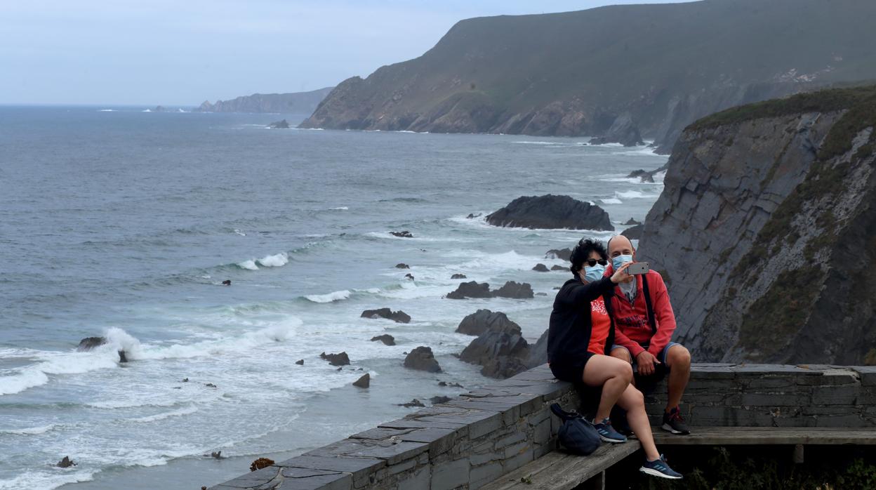 Una pareja de turistas disfrutan de los acantilados de la zona de Finisterre