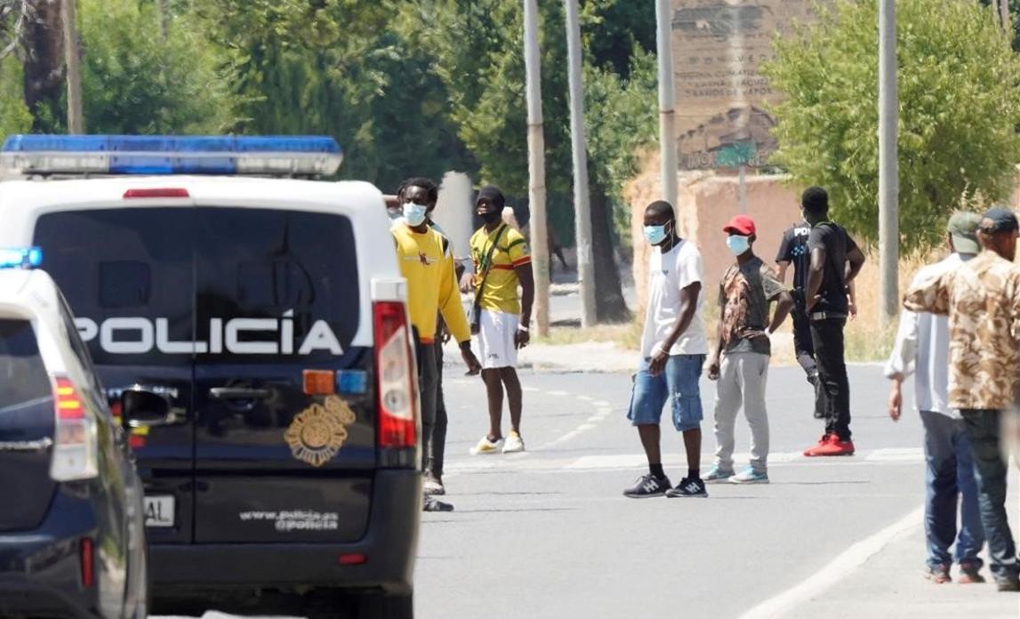 Vehículos de la Policía Nacional junto a los temporeros de Albacete