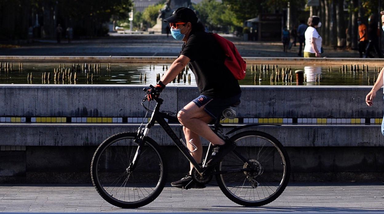 Un hombre cirucla en bicicleta por el centro de Valladolid con su mascarilla