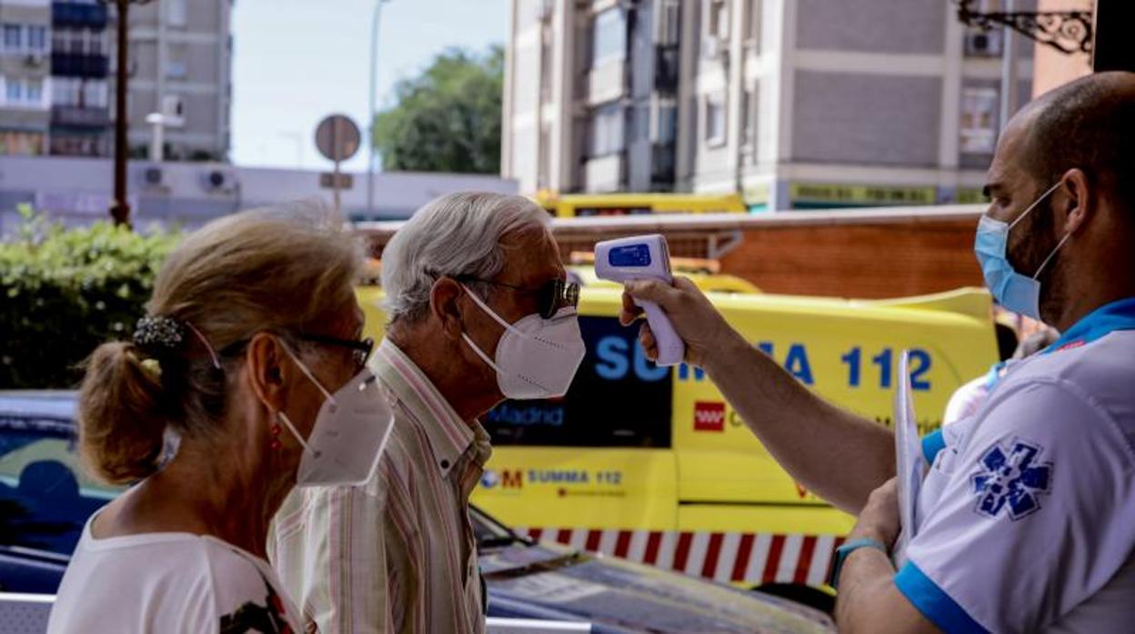 Un técnico del Summa 112 toma la temperatura a dos vecinos de Villaverde, ayer, durante los test PCR masivos