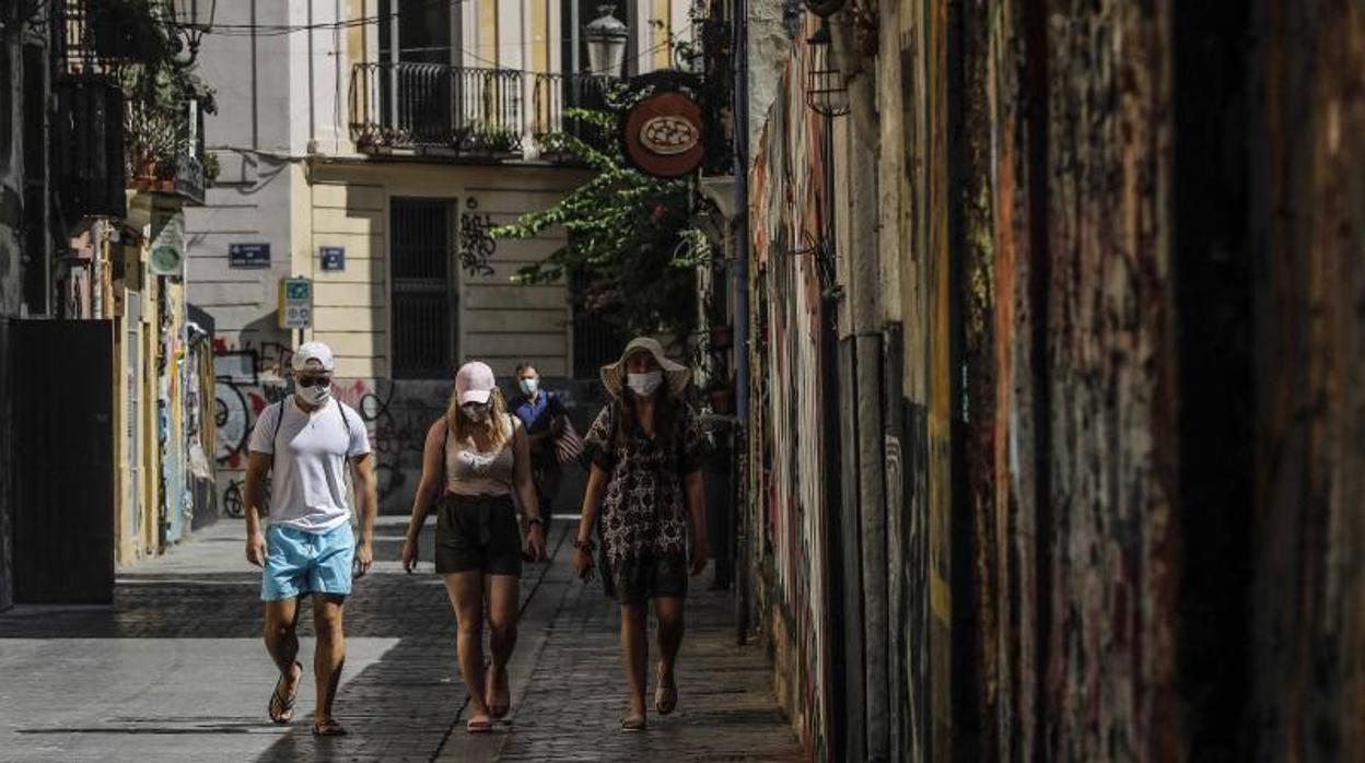 Transeúntes con mascarilla pasean por una calle de Valencia