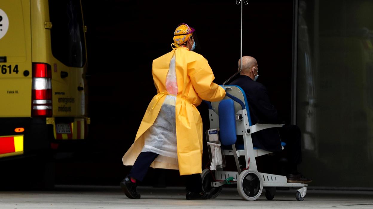 Un profesional sanitario traslada a un paciente en la entrada de urgencias del Hospital de Bellvitge, Barcelona