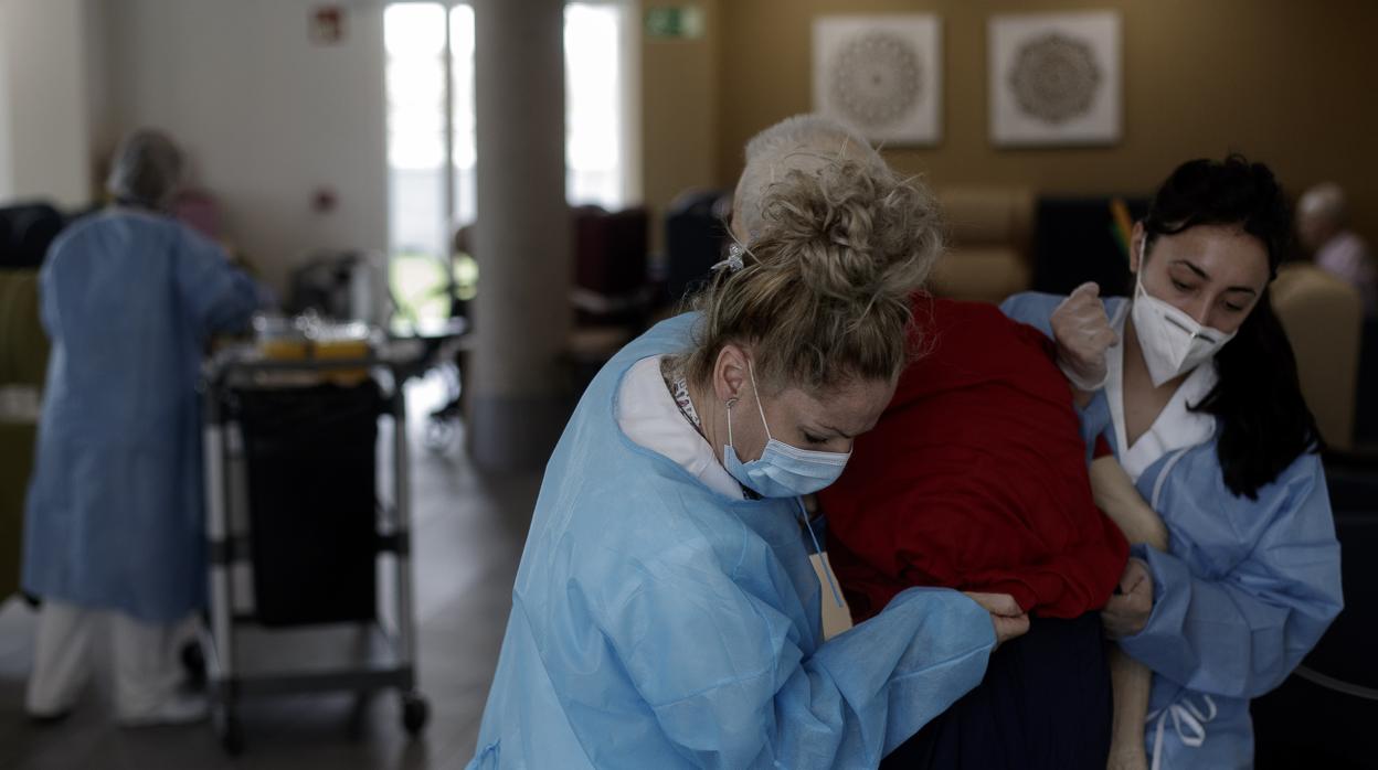 Dos trabajadoras de una residencia visten a una anciana durante la pandemia