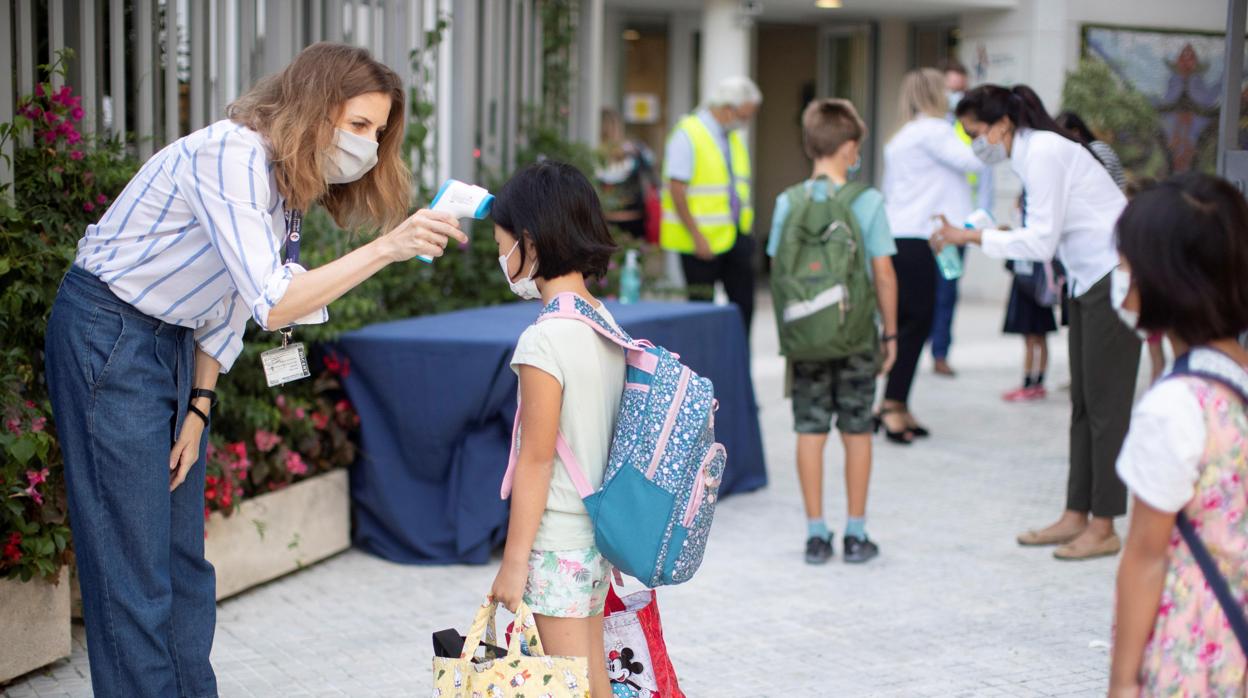 Personal docente de la escuela toman la temperatura a los alumnos en la entrada