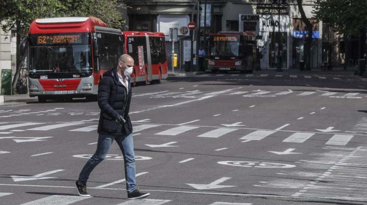 Un transeúnte pasa delante de un autobús de la EMT en Valencia