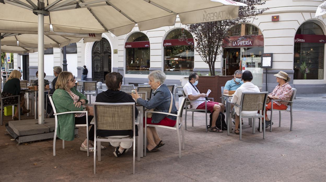 Varias personas en la terraza de un bar que tenia solo siete mesas ocupadas de dieciséis