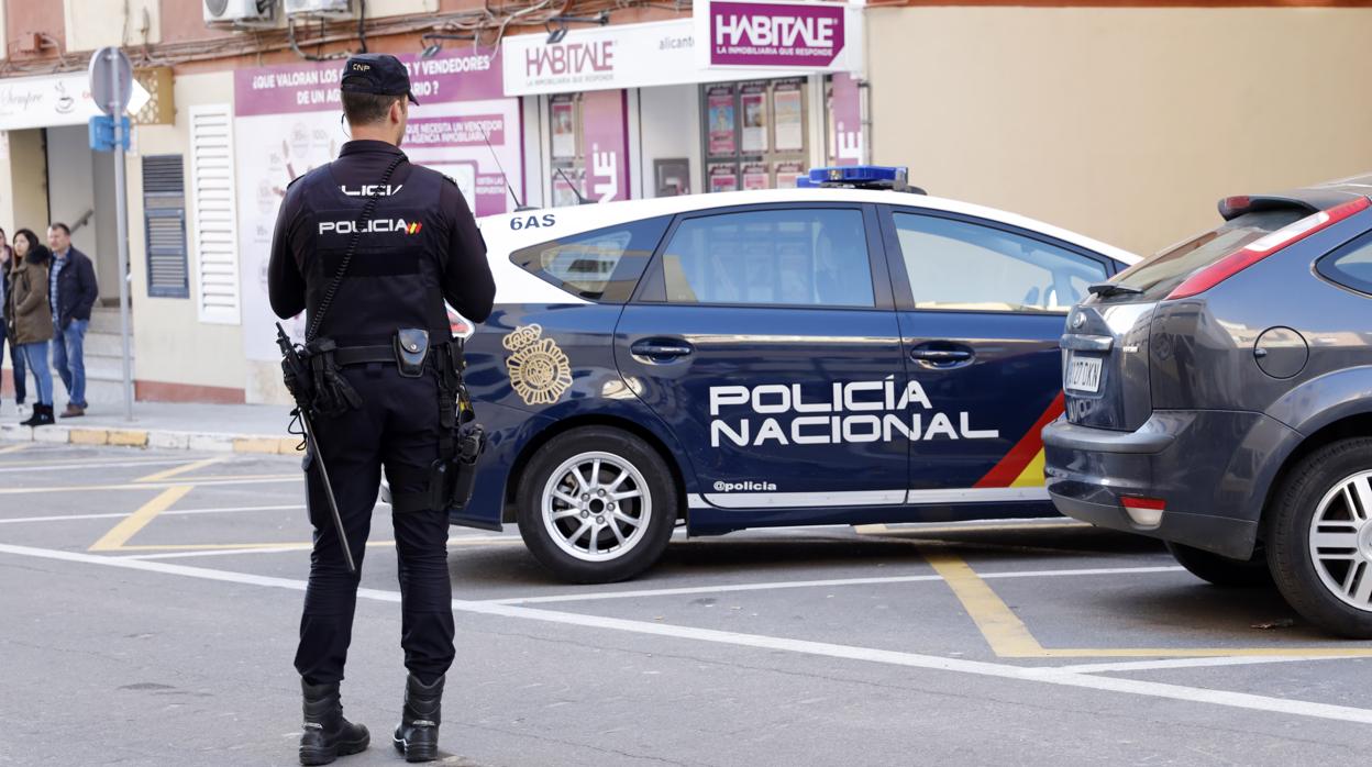 Un policía junto a un coche patrulla en una imagen de archivo