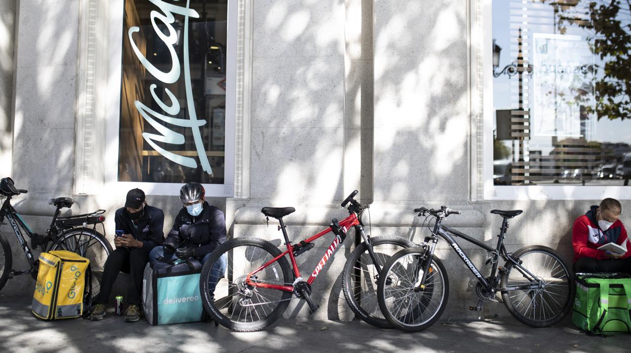 Varios repartidores esperan pedidos a las puertas de un restaurante de comida rápida