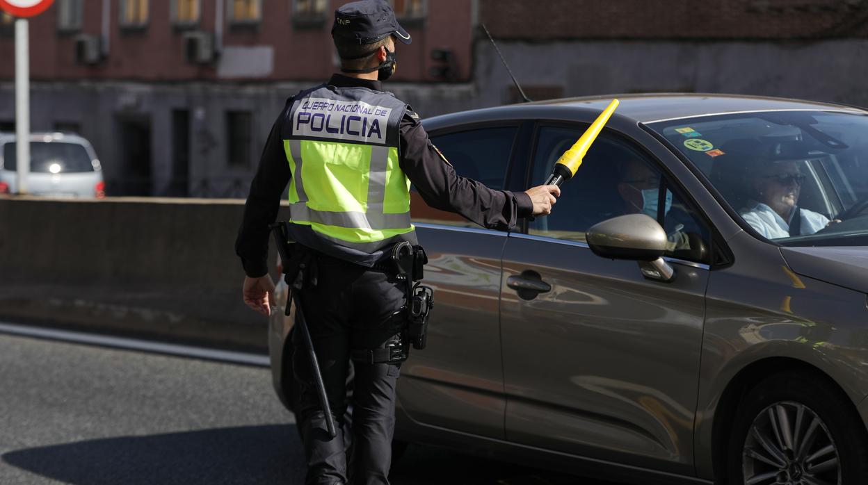 Un agente de Policía Nacional da el alto a un vehículo en un control en la carretera A-5, en Madrid, tras la declaración del estado de alarma en la región