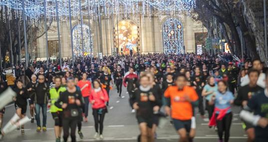 Los corredores de la San Silvestre Vallecana avanzan por la Puerta de Alcalá hacia Cibeles