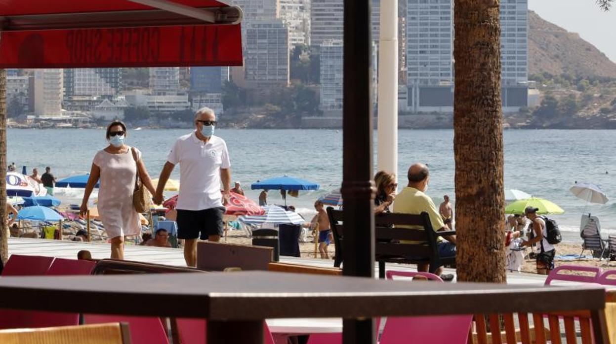 Una pareja de turistas pasean junto a la Playa de Levante en Benidorm